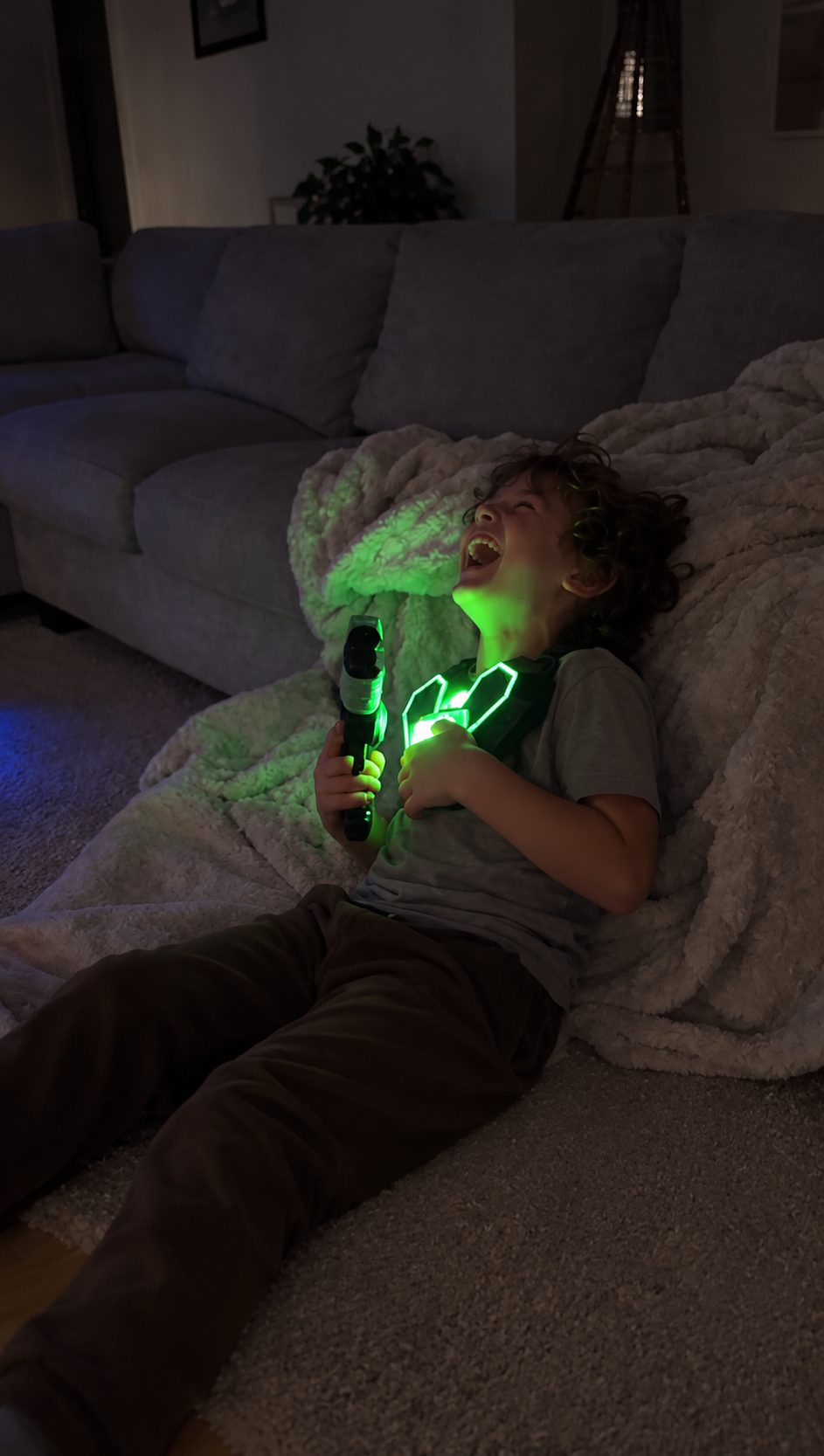 A boy laughing on the floor with his vest glowing green
